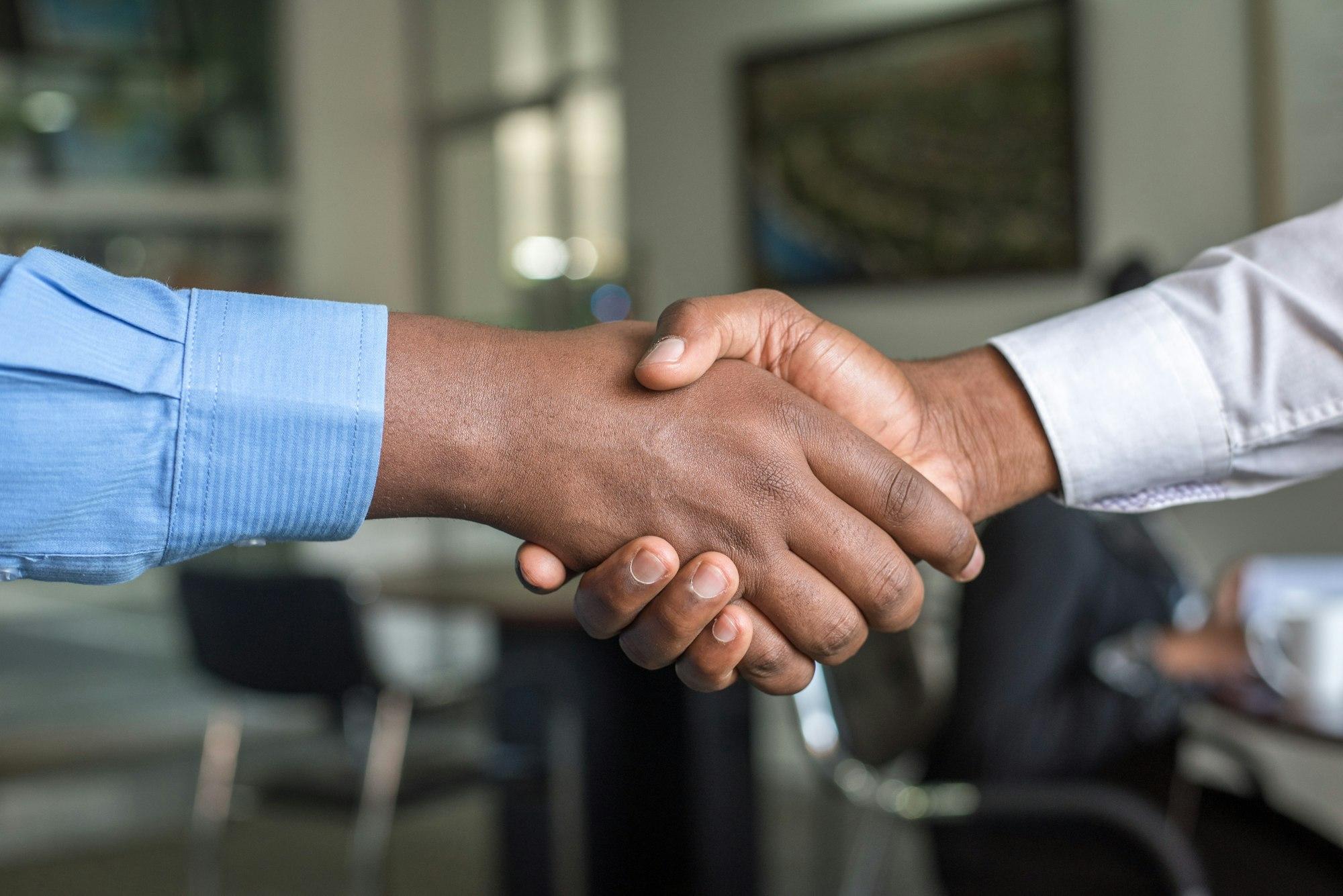Two people shaking hands across an office.