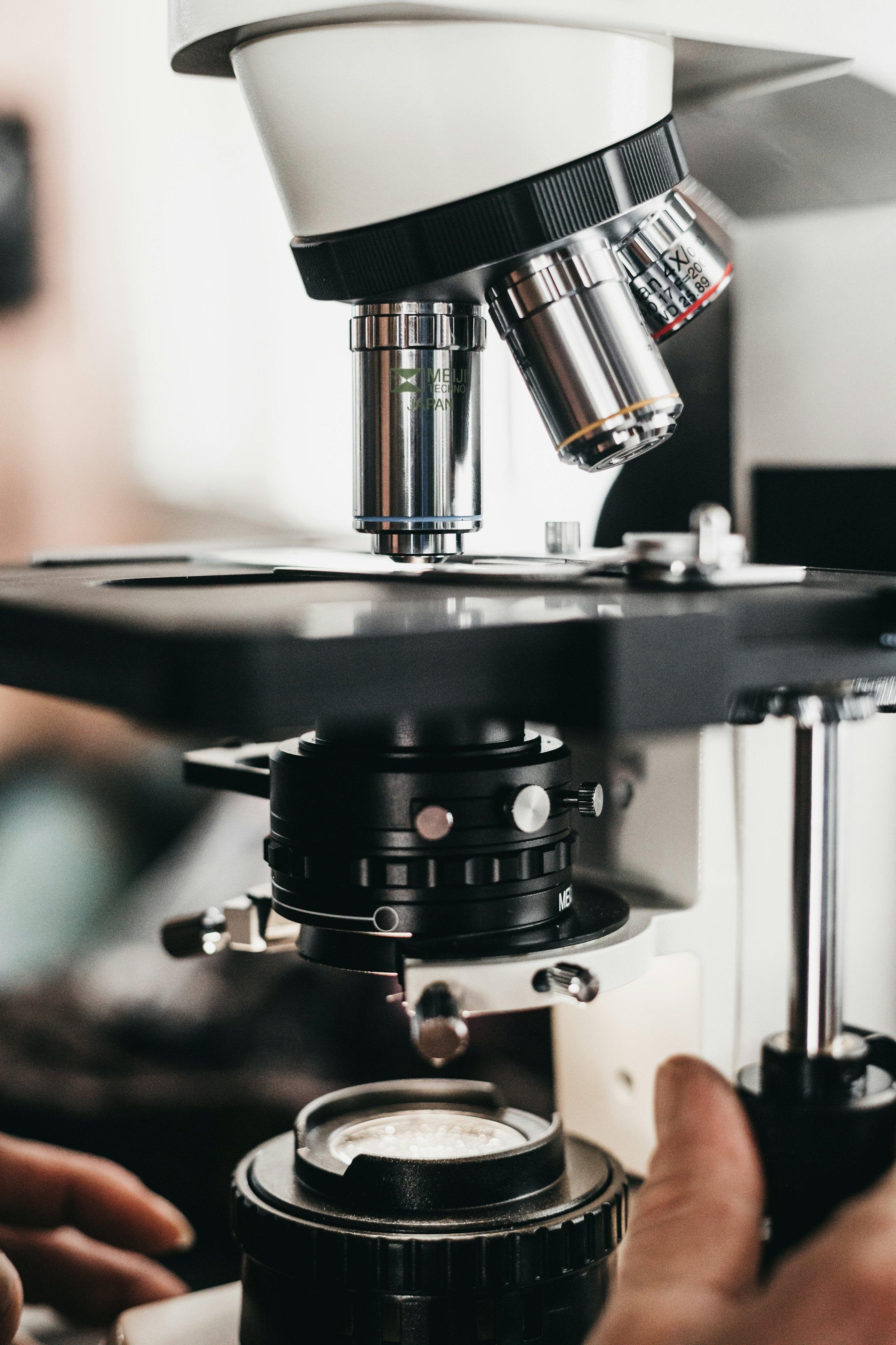A scientist adjusting a microscope.