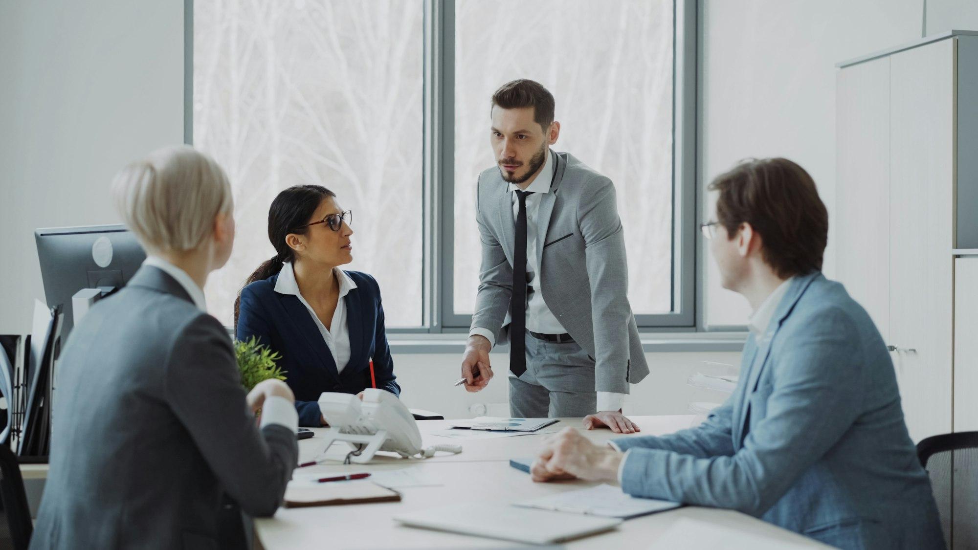 Colleagues in discussion around a meeting table.